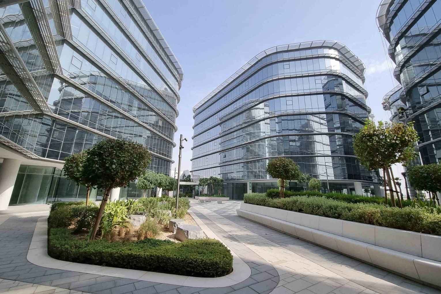 Dubai CommerCity kampüsünde cam cepheli ofis binaları ve bahçeler