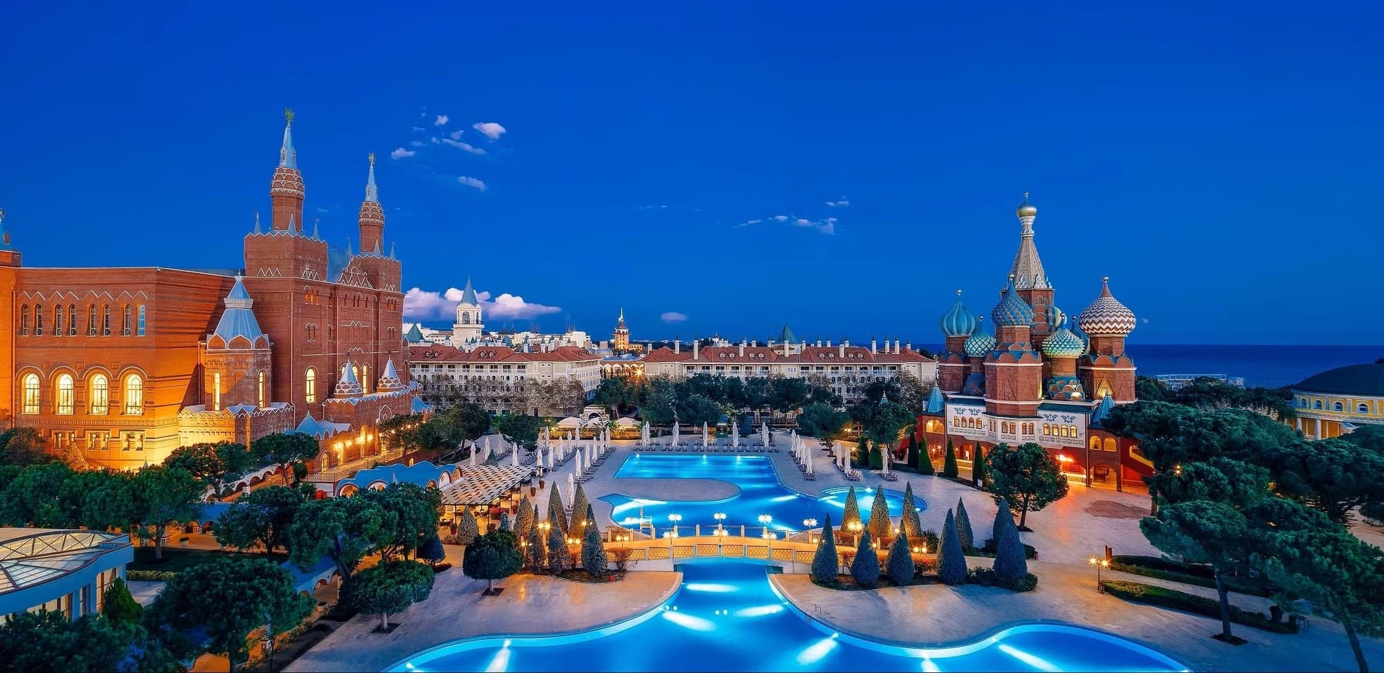 Kremlin Palace resort in Antalya at blue hour, with its domes, palace halls and lit pools by the Mediterranean